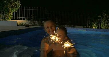 Woman and Boy with Sparklers in Pool video