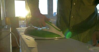 Man ironing shirt in sunny room video