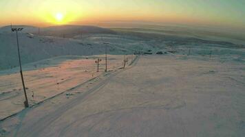 Ski-run and snowy hills at sunset, aerial view video