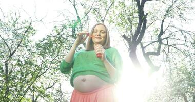 gravid kvinna blåser tvål bubblor utomhus- video