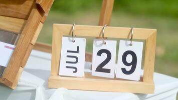 Wooden calendar date of 29 July on green background photo