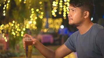 Asia Man drinking beer. Side view of handsome young man drinking beer while sitting at the bar counter. photo