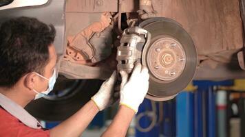 asiático hombre coche mecánico reemplazando un coche neumático en garaje taller. . auto servicio, cuidado del automóvil centrar elimina el rueda, reparar y mantenimiento de el coche en servicio. foto