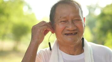 Asian elderly man or a grandfather, a happy retired man with headphones listening to radio music before exercising in the park. photo
