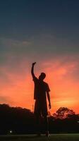 AI Generative Silhouette of man in the evening watching beautiful sunset with arms raised up outstretched cheering and happy photo