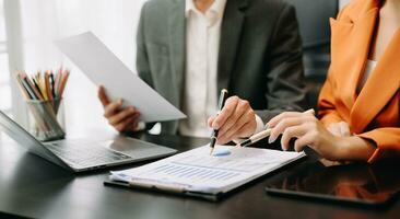 Business documents on office table with smart phone and calculator digital tablet and graph business with social network diagram and two colleagues discussing data working in the office photo