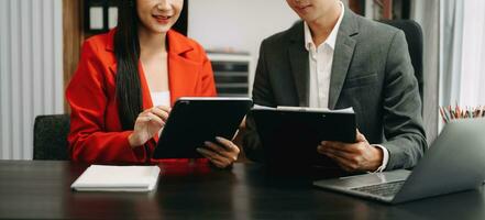 Business documents on office table with smart phone and calculator digital tablet and graph business with social network diagram and two colleagues discussing data working in the office photo