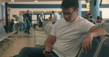 Young man using cell phone in airport lounge video