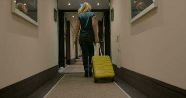 mujer caminando a lo largo el hotel paso con carretilla bolso video