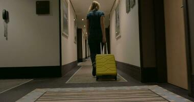 Woman with suitcase walking in hotel corridor video