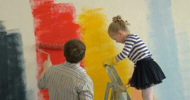Father and daughter painting walls in bright colors video