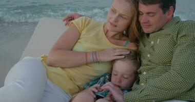 Young parents and child spending leisure time by the sea video