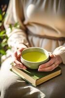 calma escena de manos de plataforma un verde té taza con un atención plena libro cerca ai generativo foto