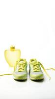 Conceptual health and lifestyle image with running shoes, water bottle, and a heart-shaped measuring tape symbol photo