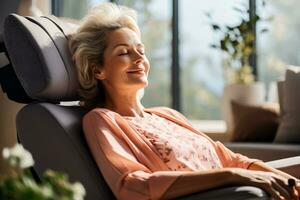 Senior woman lounging and napping on an electric massage chair in the living room photo