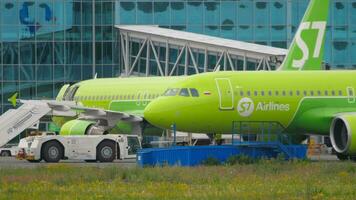 NOVOSIBIRSK, RUSSIAN FEDERATION JULY 15, 2022 - Tugboat towing aircraft of S7 Airlines on the runway at Tolmachevo airport. Tourism and travel concept video