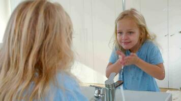 menina lavando face e sorridente às reflexão video