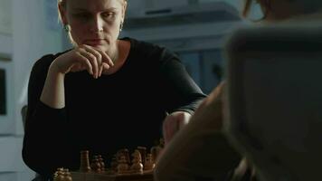 mam en zoon gezicht uit in een vriendelijk spel van schaak video