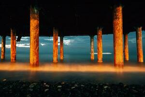 Professional high quality photo. iron columns at the seashore. Photo of waves on a long exposure. Evening photo of the sea and columns with rust