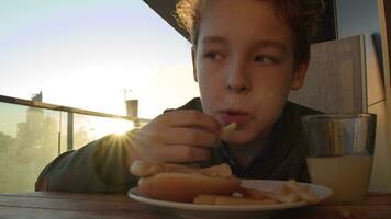 Boy eating French fries with orange juice for breakfast video
