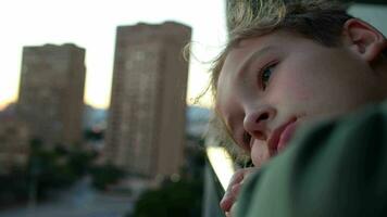 Sad and lonely teenager boy looking at the city from the balcony video