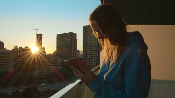 donna con smartphone su il balcone nel il città a Alba video