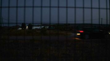 Car passing by, night view from behind the wire metal fence video