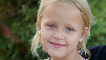 alegre pequeno menina com grande azul olhos ao ar livre video