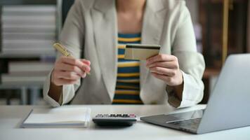 Business woman using calculator with credit card for shopping internet online and financial business strategy video