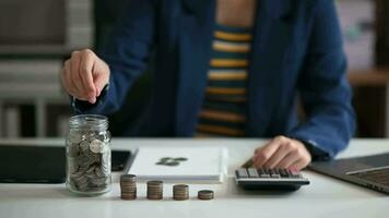 homme d'affaires détenant des pièces de monnaie mettant dans le verre avec l'aide d'un smartphone et d'une calculatrice pour calculer le concept d'économie d'argent pour la comptabilité financière video