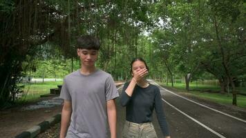 Male and female asian young teen enjoy walking on the street in public park. video