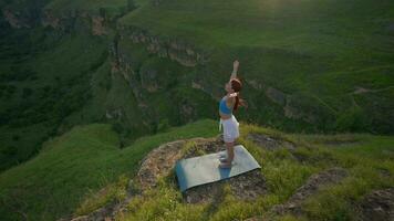 ioga exercite-se do fêmea atleta. jovem saudável mulher fazendo ioga dentro a montanhas durante nascer do sol. bem estar e saudável estilo de vida, zen conceito. lento movimento. video