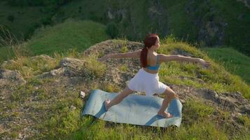 atlético mujer haciendo yoga poses en parte superior de un montaña durante puesta de sol. Deportes niña trenes y lo hace extensión ejercicios en el montañas. sano estilo de vida, zenismo, rutina de ejercicio concepto. lento movimiento. video