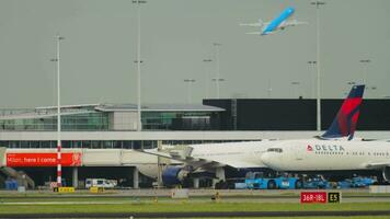 AMSTERDAM, THE NETHERLANDS JULY 27, 2017 - Side view of passenger plane Boeing 767 of Delta Airlines taxiing at Schiphol Airport, Amsterdam. Tractor towing an airliner. Tourism and travel concept video