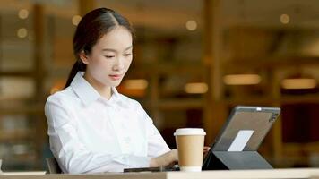 Woman typing documents in laptop discussing work while holding coffee in the morning video