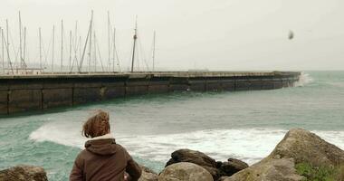 Child throwing a rock into the wavy ocean video