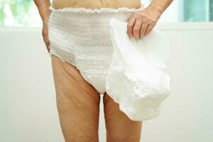 Asian senior woman patient wearing adult incontinence diaper pad in hospital. photo