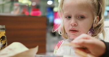 criança comendo dentro cafeteria com família e usando Móvel durante almoço video