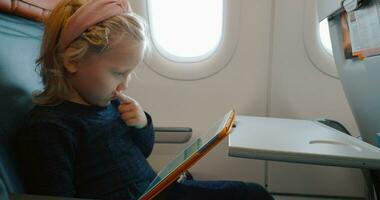 bambino utilizzando digitale tavoletta nel il aereo video