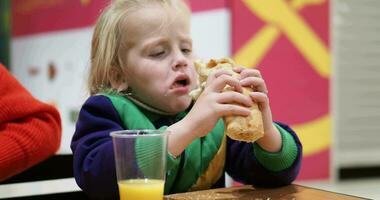 Kid eating hot dog with orange juice video