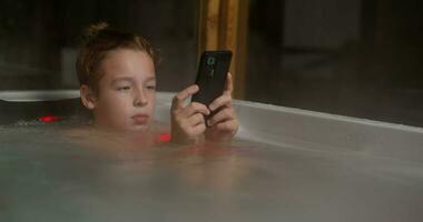 garçon dans Extérieur salle de bains avec mobile téléphone video
