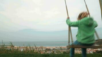 pequeño niña balanceo en contra el escena de nazaré costa en Portugal video