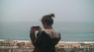 jongen nemen afbeeldingen van toneel- nazaré kust en oceaan, Portugal video