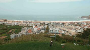 Boy swinging and observing coastal resort town Nazare, Portugal video