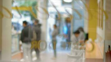 Cafeteria guests waiting in queue, blurry view through the glass video