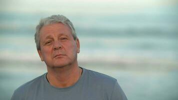 Serious and calm retired man portrait against the ocean video