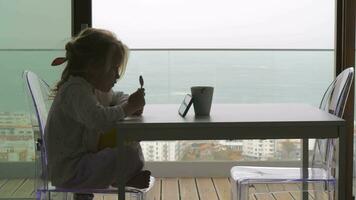 peu enfant attendre pour petit déjeuner et en train de regarder vidéos sur le téléphone video