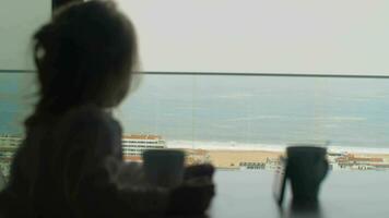 menina tendo café da manhã com desenhos animados contra oceano cena lado de fora video