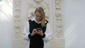 Woman using mobile by the facade wall with grapes stucco work video