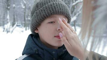 Boy getting winter skin care from mom, applying face cream video